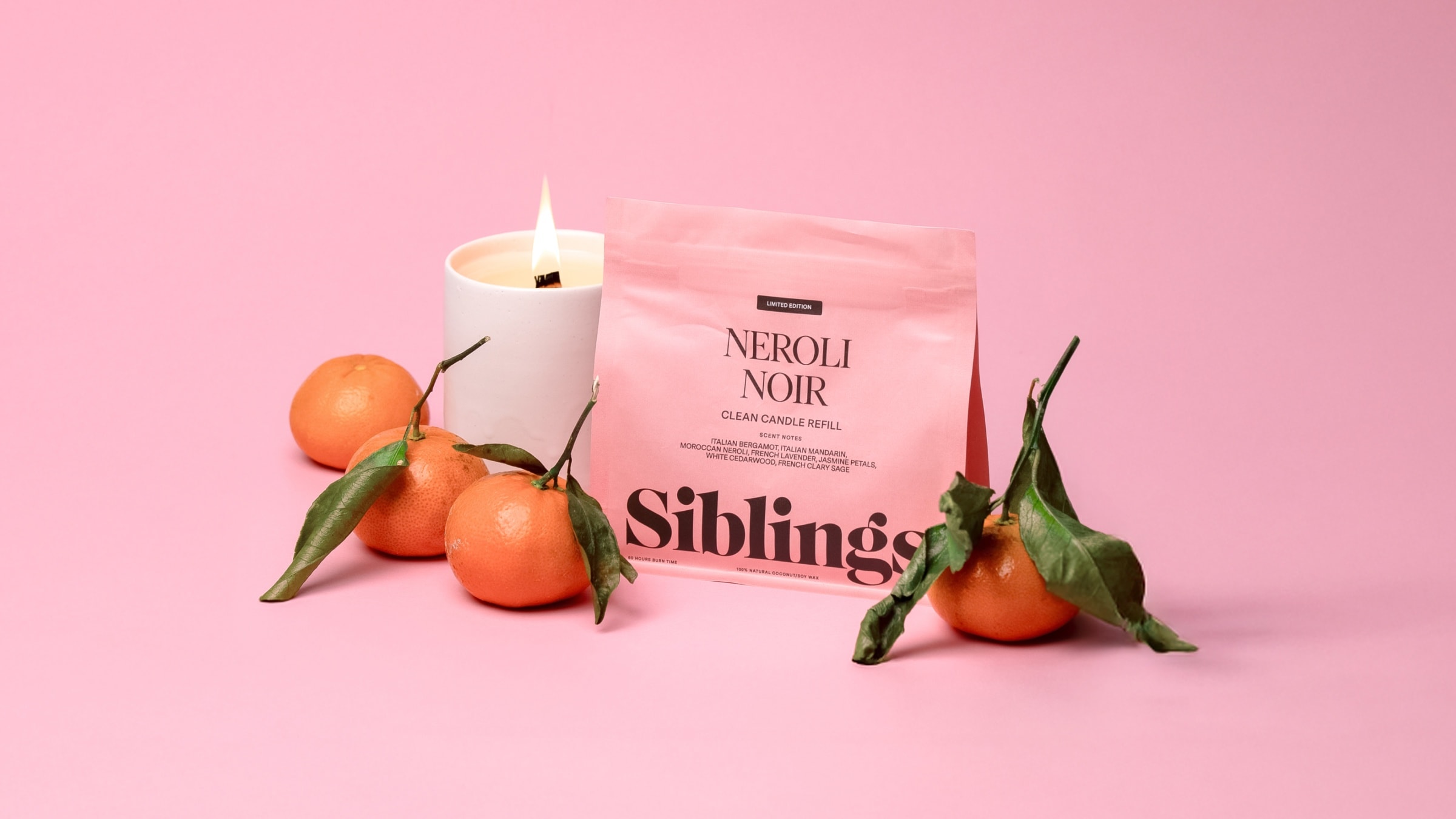 Siblings Neroli Noir clean candle refill with lit candle and mandarins on pink background
